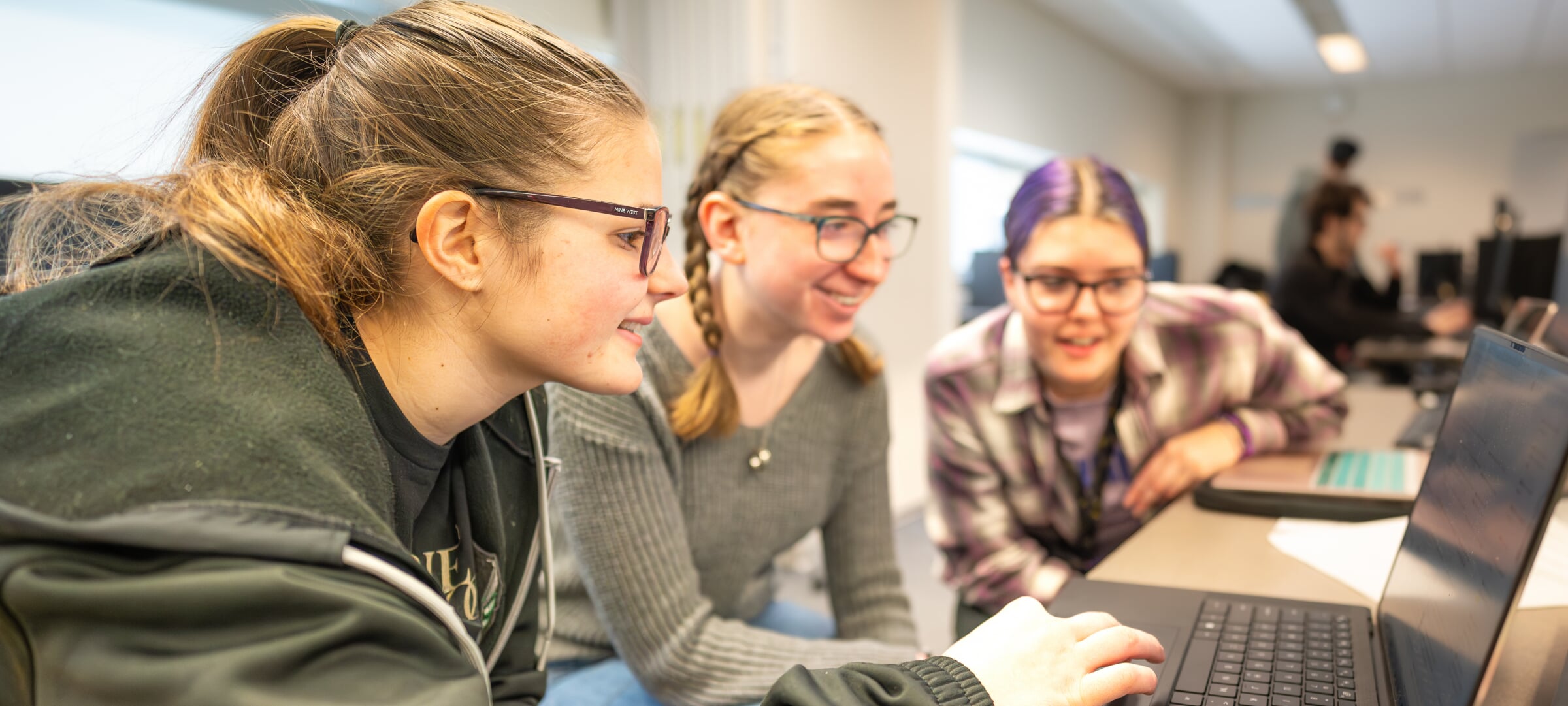 Three girls working on a laptop.