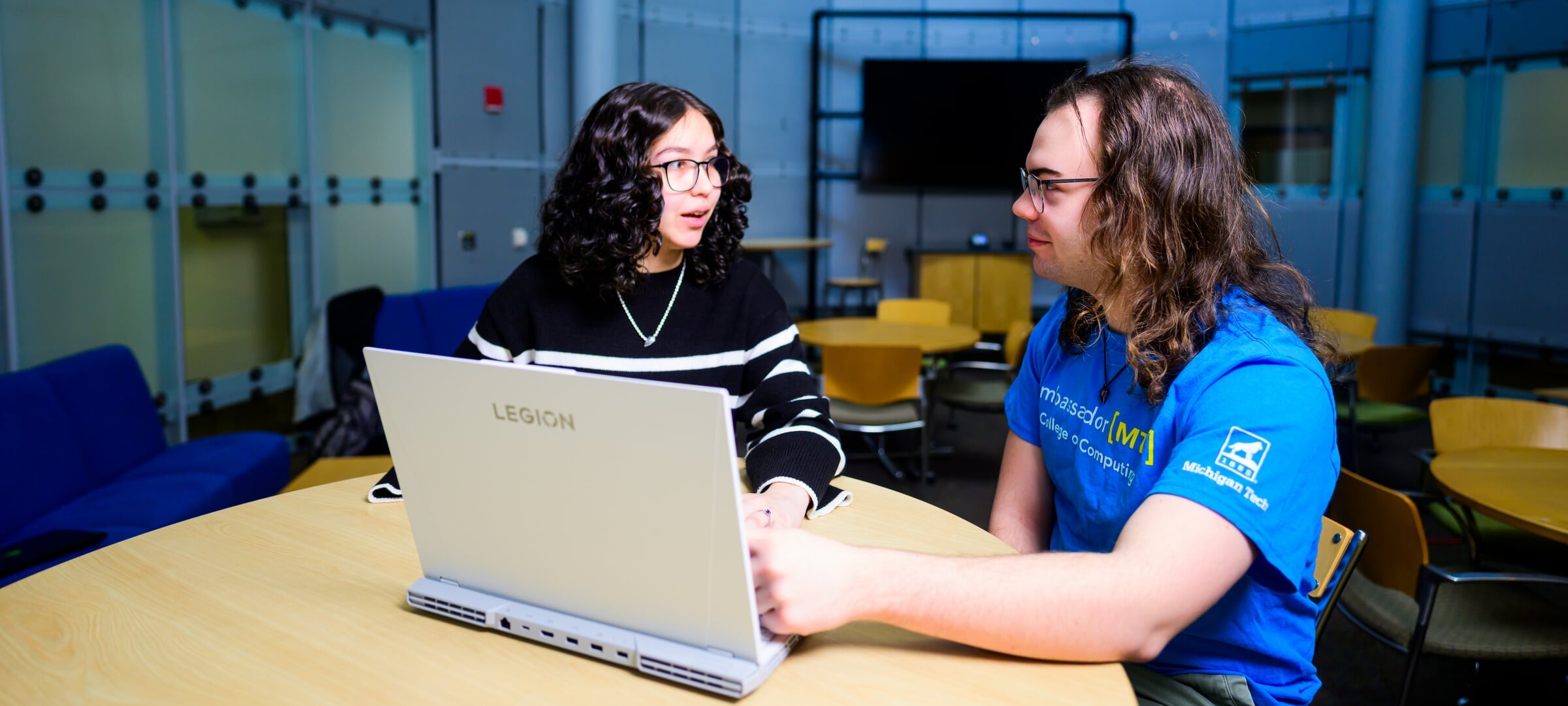 Two students sitting at a round table with a laptop.