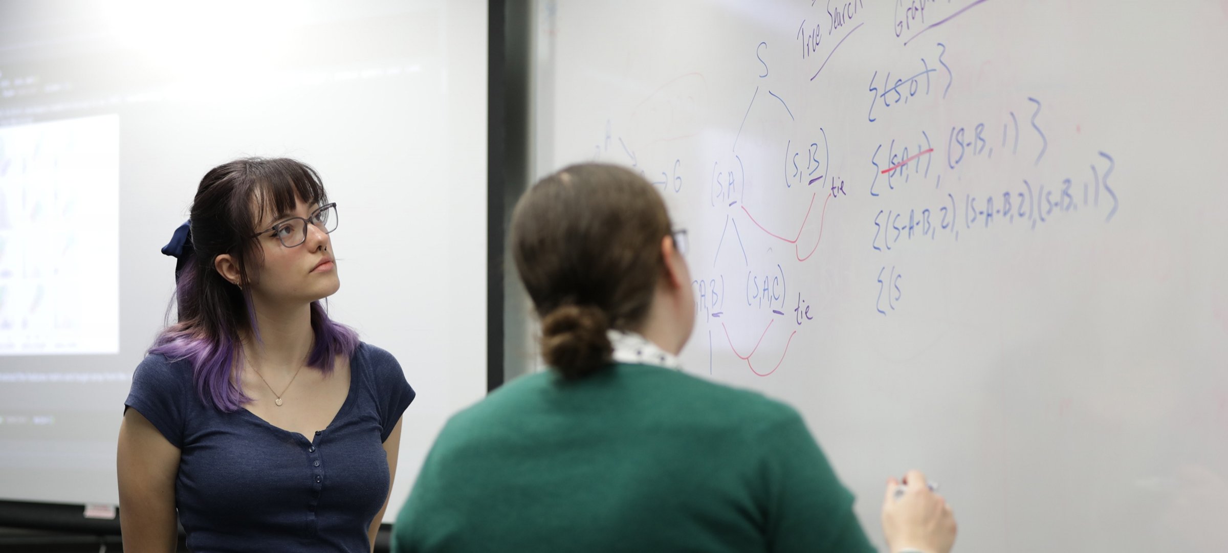 Professor Brown with Data Science student looking at an equation on the board.