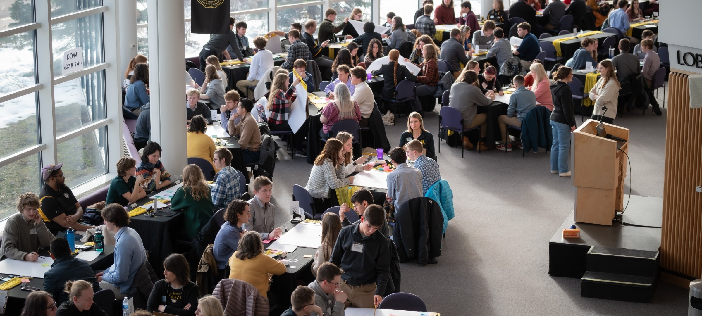 Students sitting together at tables in the lobby of the Rozsa Center at Michigan Tech.