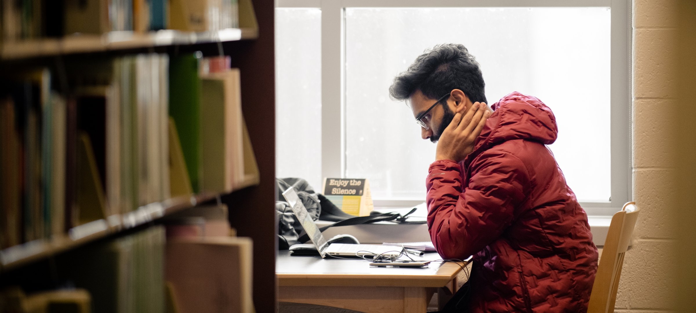 Student sitting in the library at the end of a stack shelf