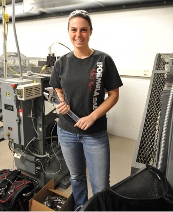 Student holding a large wrench in a machine shop.