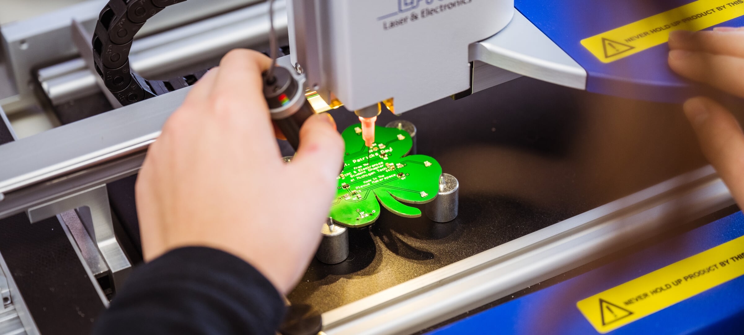 Someone working with a clover-leaf shaped circuit board