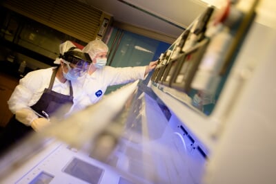 Two people wearing PPE in a lab setting