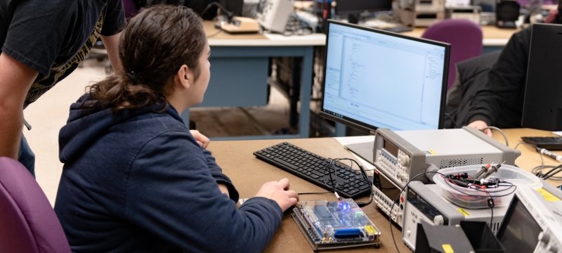 A student working with computer equipment. 