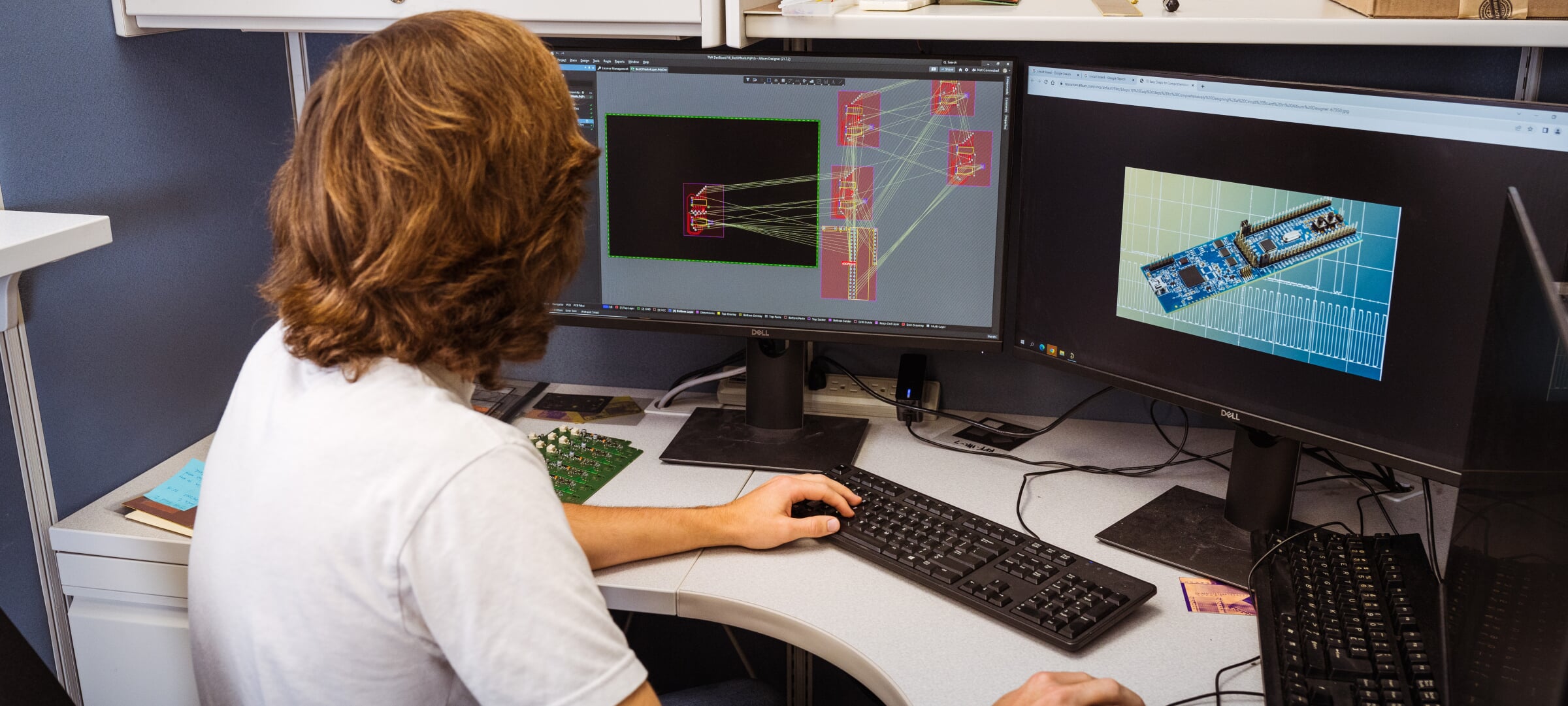 A student looking at two monitors displaying computer engineering materials