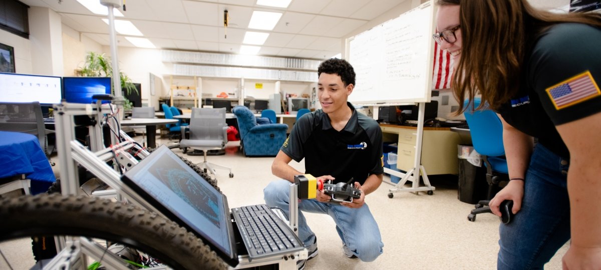 Two students looking over a robot with screen.