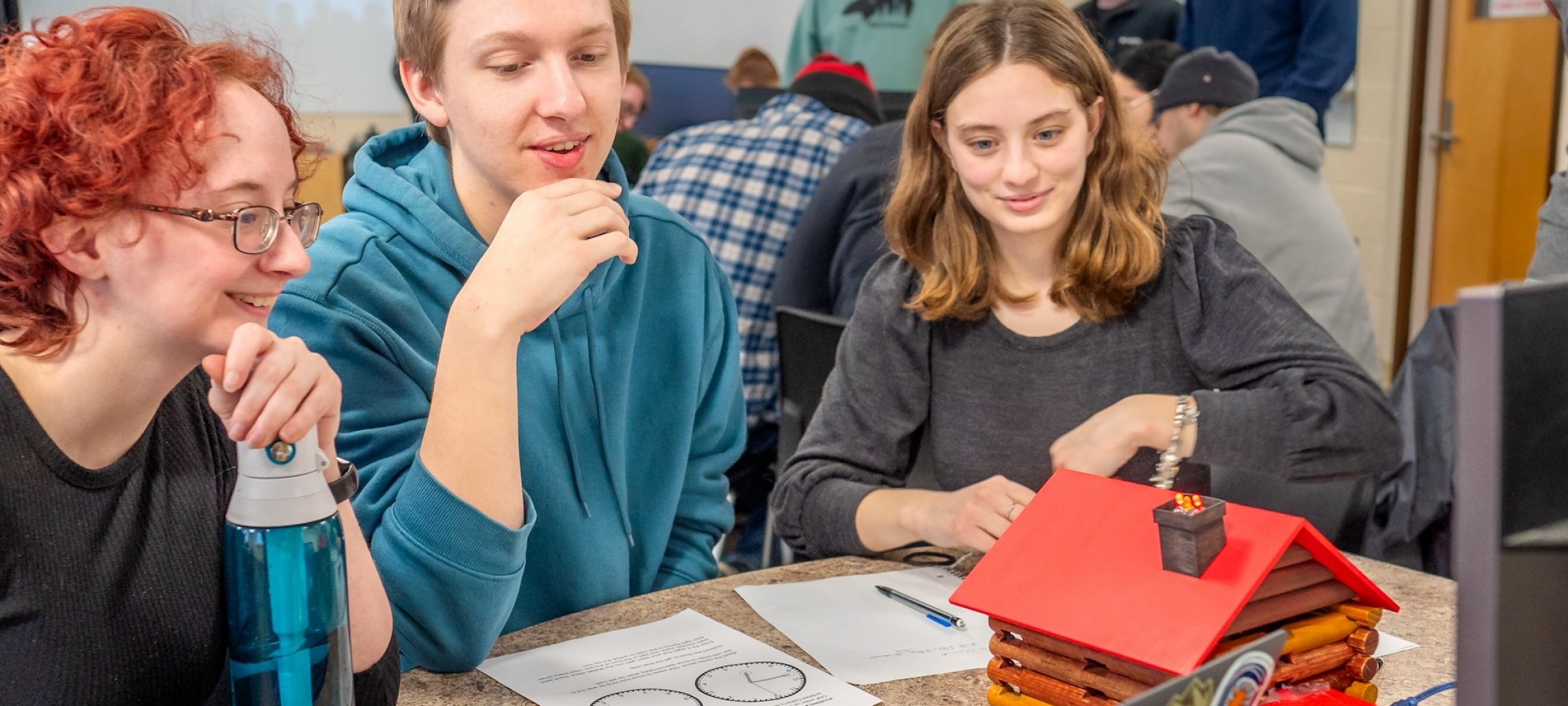 Students work on an engineering prototype at a table.