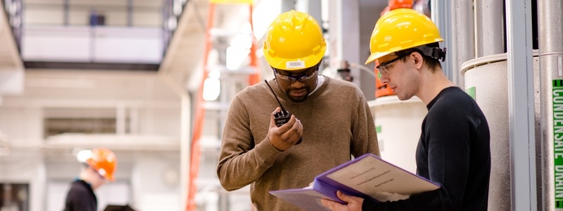 Safety coordinators discussing standards in a hardhat area.