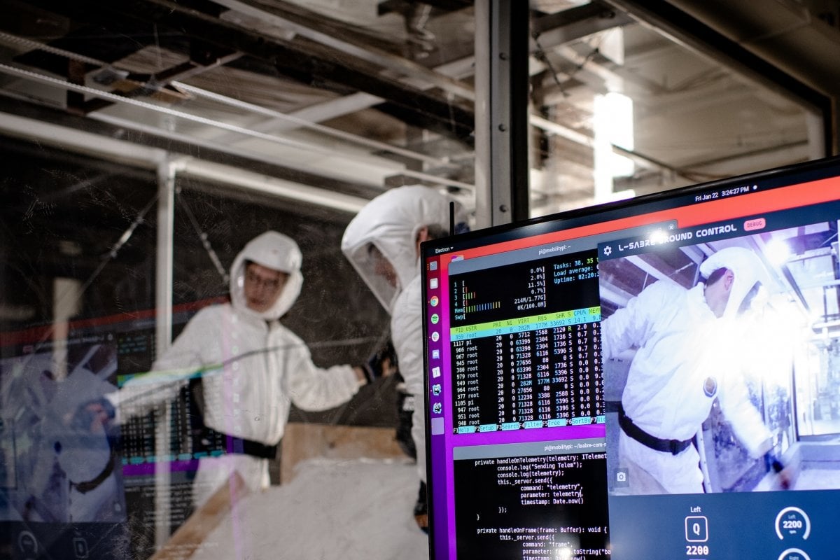Researchers in suits with an electronic display in a lab.