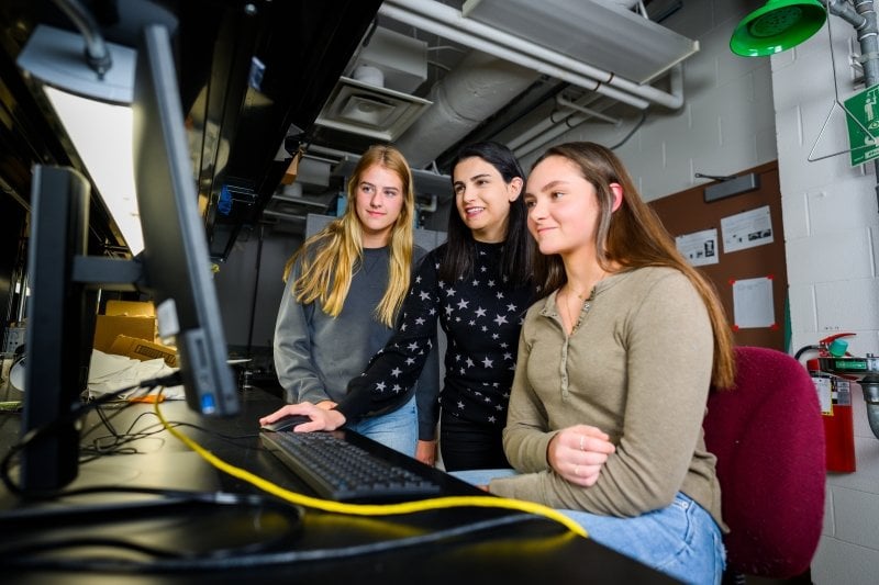 Two students with faculty at a computer.