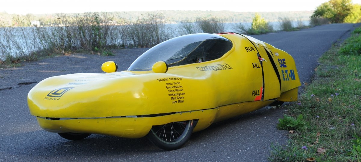 An oddly-shaped supermilage car. It's low to the ground and shaped like a cross between a banana and slug.