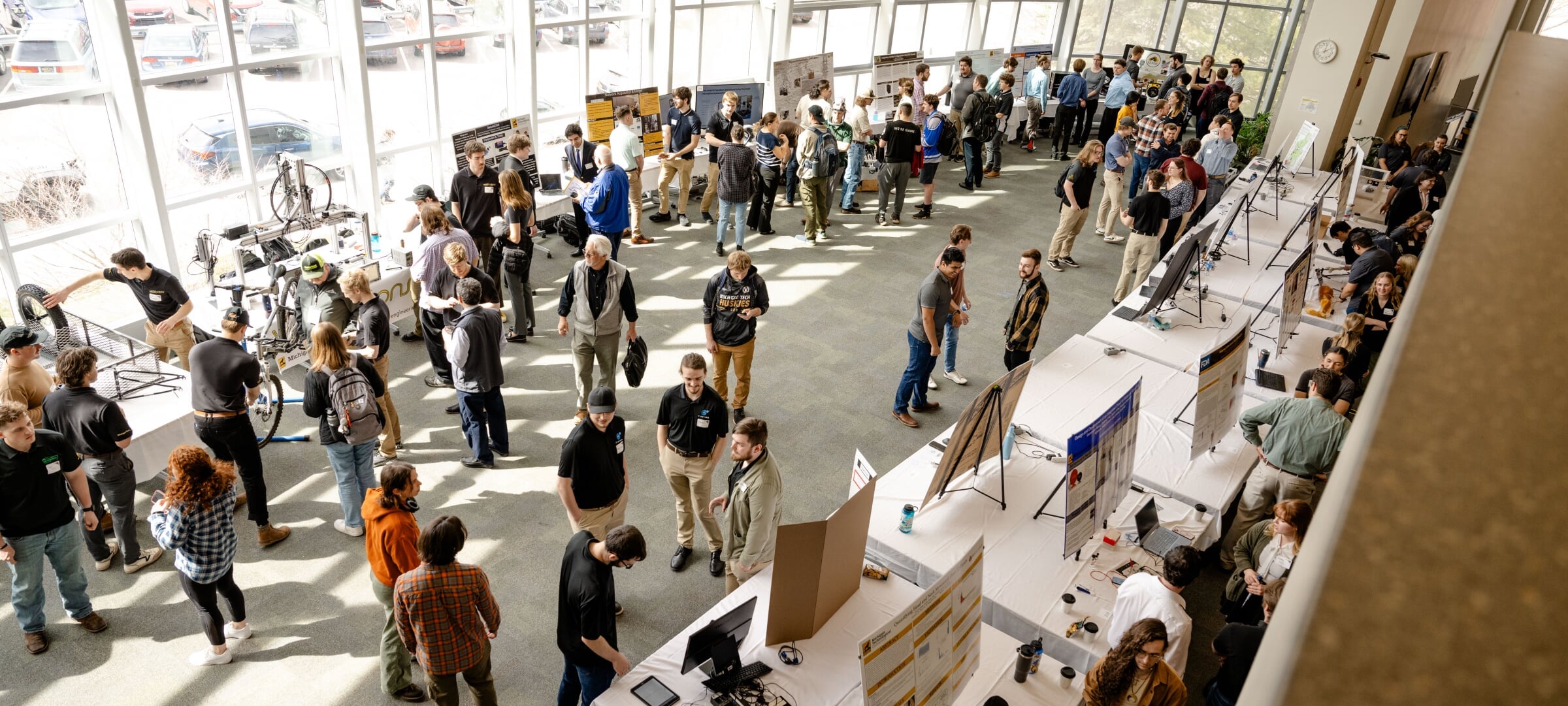 overhead view of design expo 2024 showing students and judges standing next to their tables and poster displays
