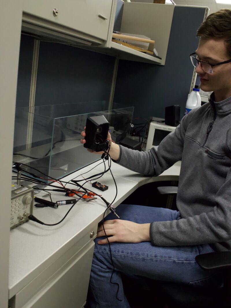 Ryan McKendry holding a speaker used in the blue laser communication project