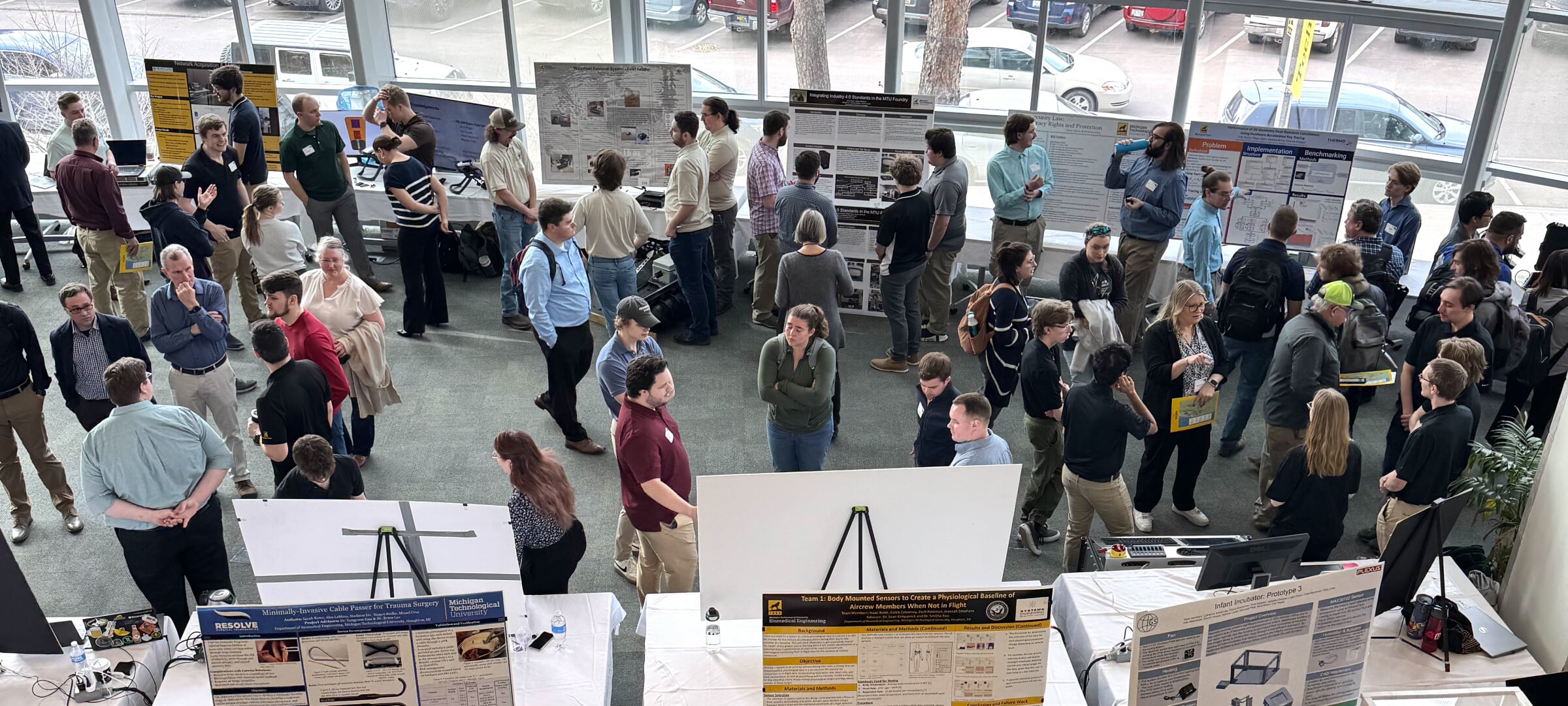 overhead view of design expo 2024 showing students and judges standing next to their tables and poster displays