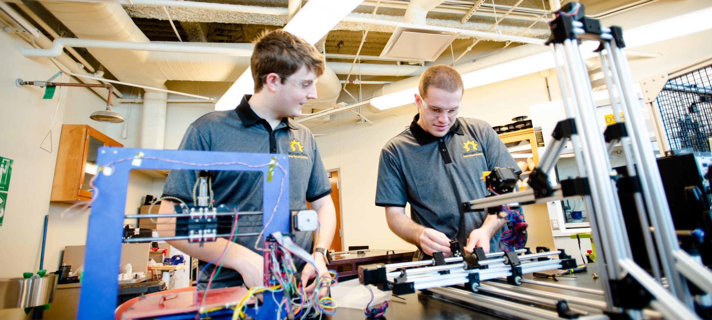 Two student working at a table in front of electronic equipment