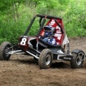 A mini baja car races on a dirt track