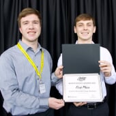 two students holding a certificate for first place