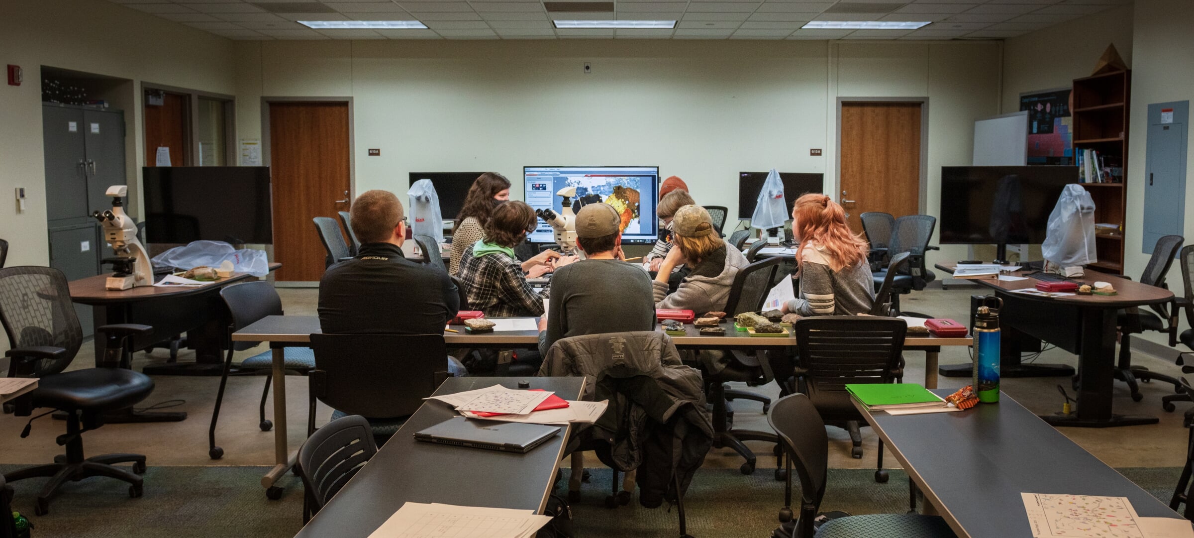 View of a classroom with a group of students working in a group around tables in the center