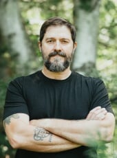 headshot of person with crossed arms and black tshirt