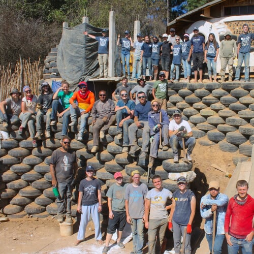 group of volunteers standing around a wall of recycled tires