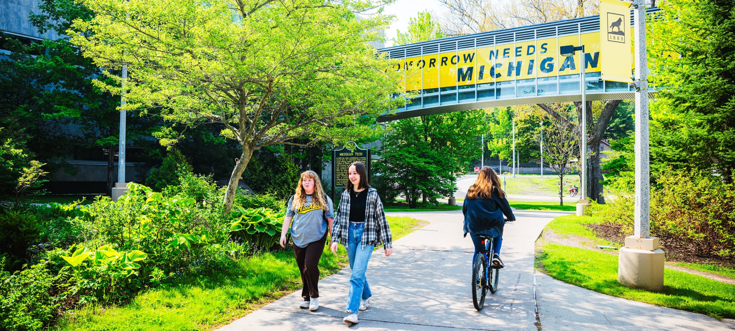 student walking and biking through the Michigan Tech campus