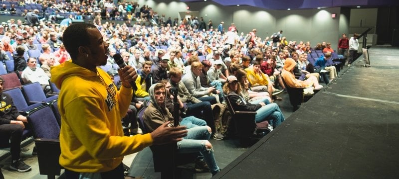 Student standing to ask a question in the Rozsa theater with audience behind