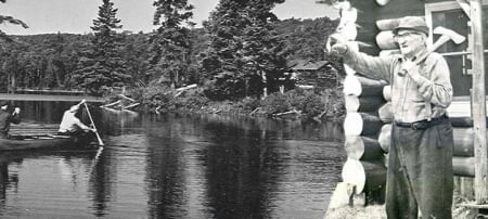 Black and white photo of people with an axe and canoeing.