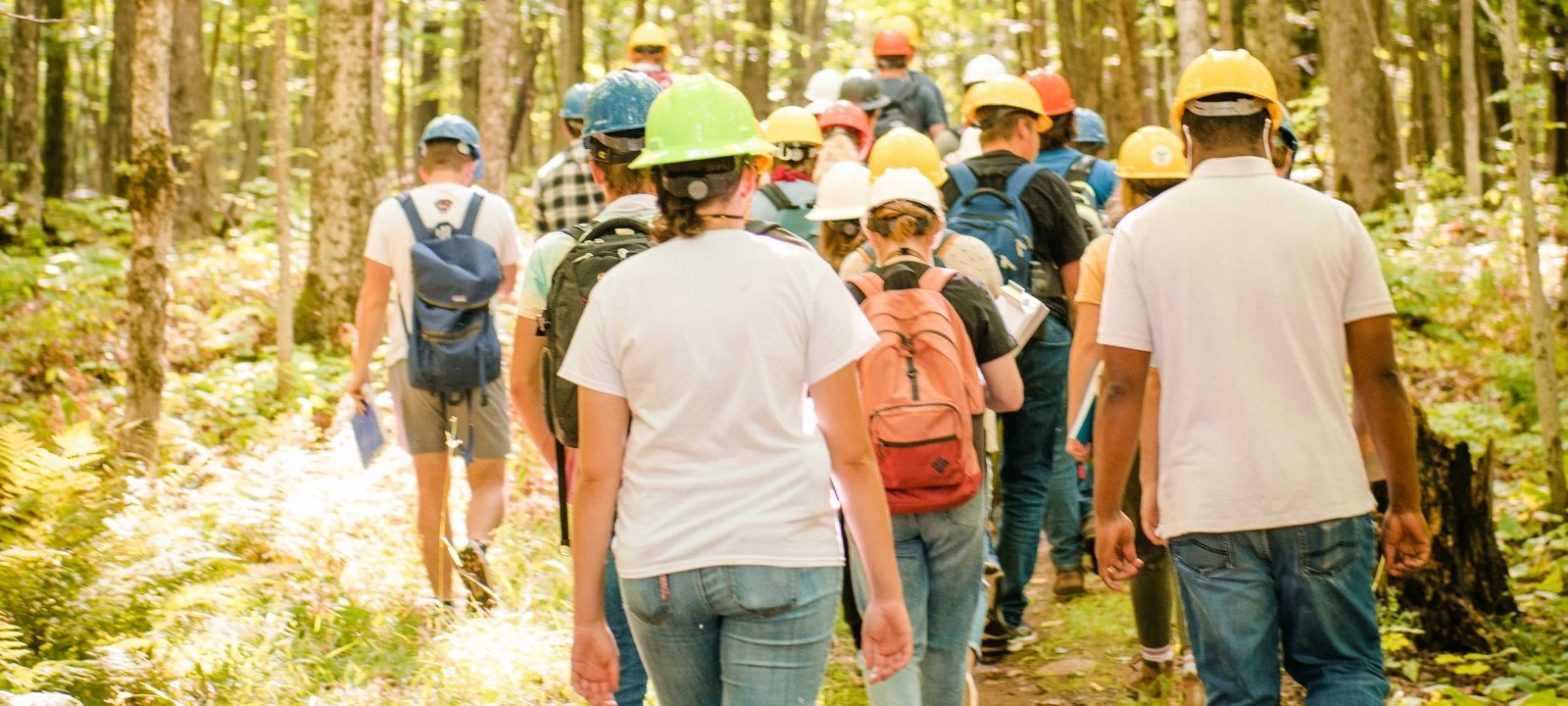 Students walking in a group in the forest wearing hardhats