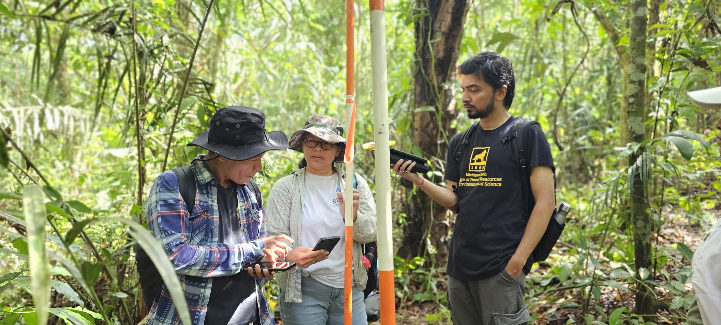 Faculty with researchers from South America in a forest using Advanced GIS.