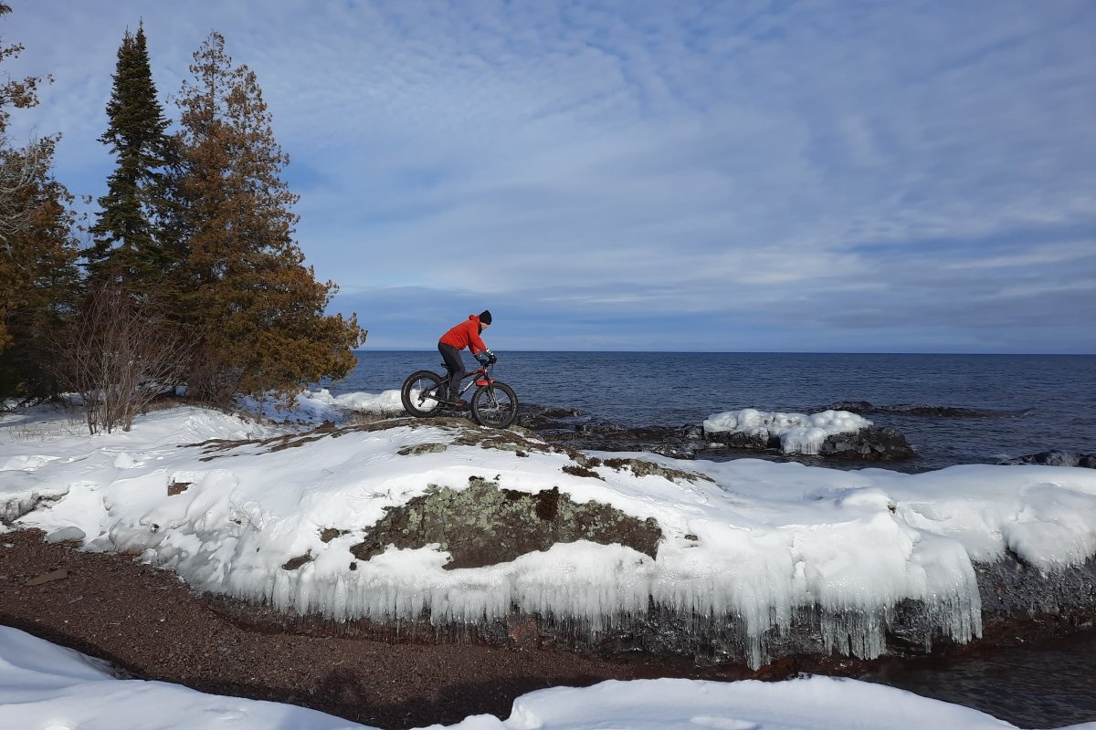 A person riding on a bike on the coast of a beach