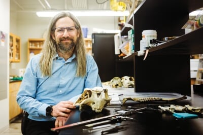 John Vucetich standing in a lab with animal bones on the table.