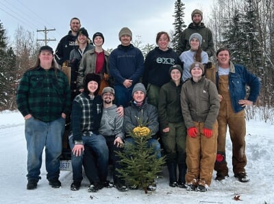 Forestry Club students pose for a photo with one of the tiny trees they cut.
