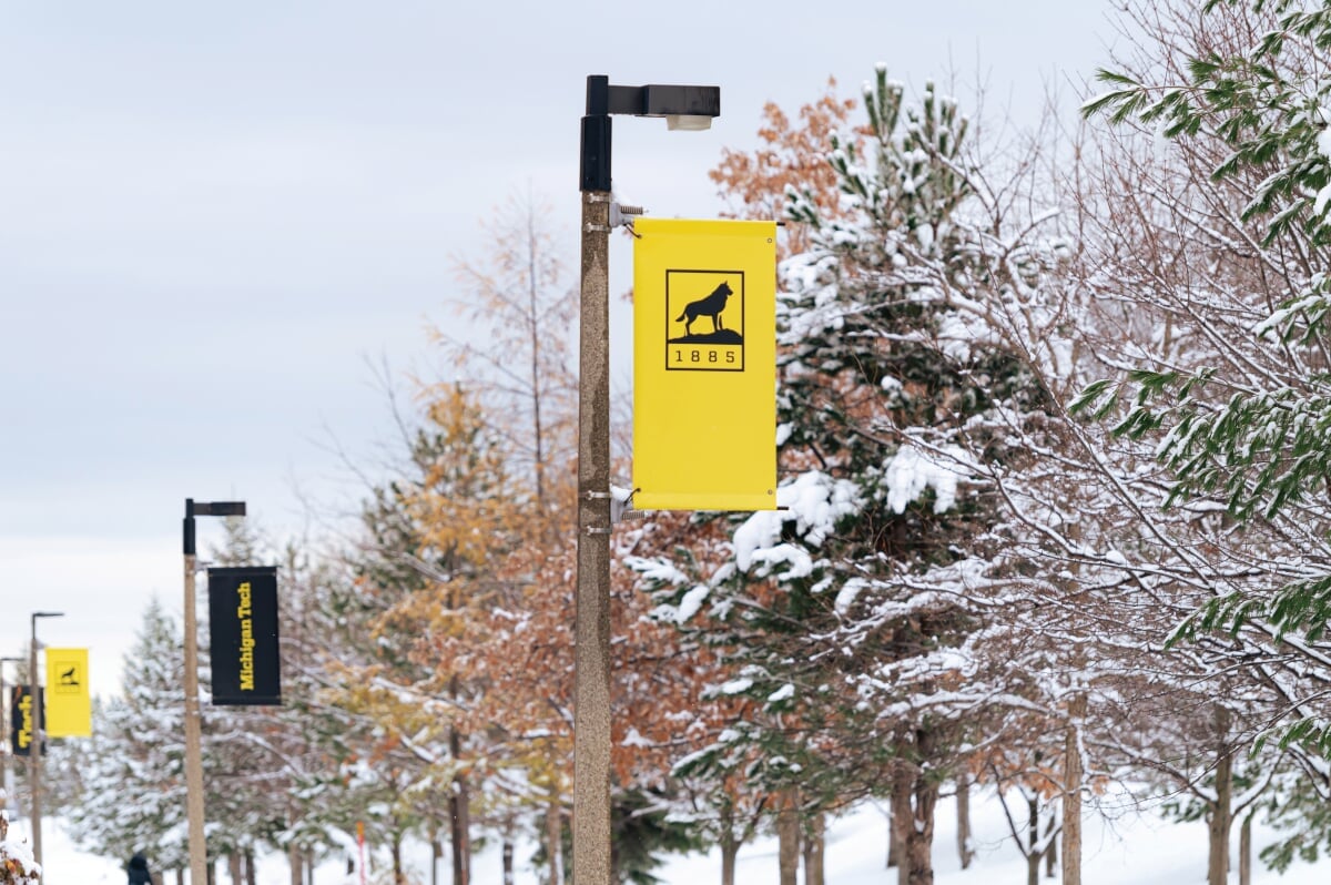 Michigan Tech logo flags on campus light poles in the winter.