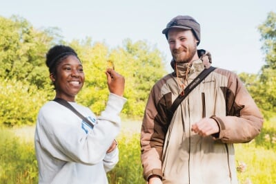 Student holding a small bird while a professor watches.