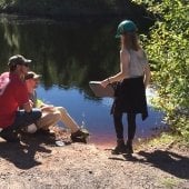 Student by a stream with hard hats