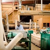 Student with protective eyewear and lab coat pushing wood through a machine in a lab