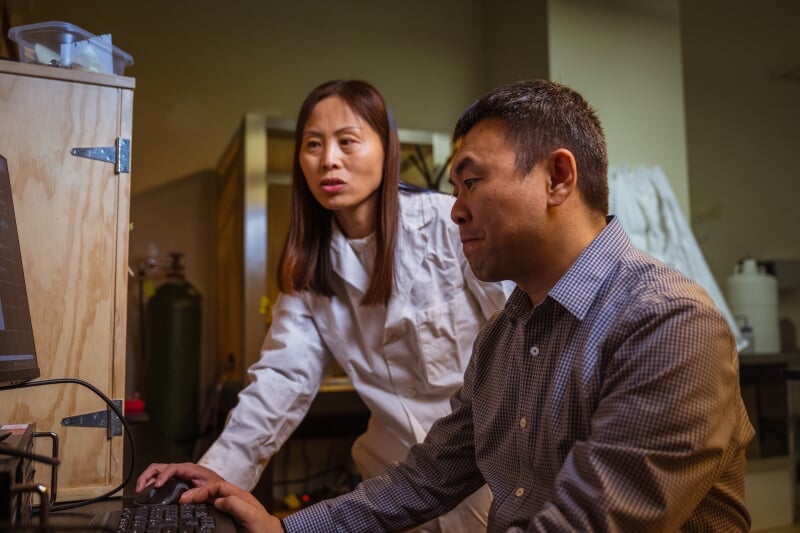 Tracy Yu with an assistant looking at a computer.
