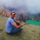 Student sitting on a hill overlooking a foggy lake.