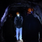 People wearing hardhats and lights in a dark mine.
