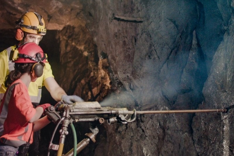 Two people drilling inside a mine.