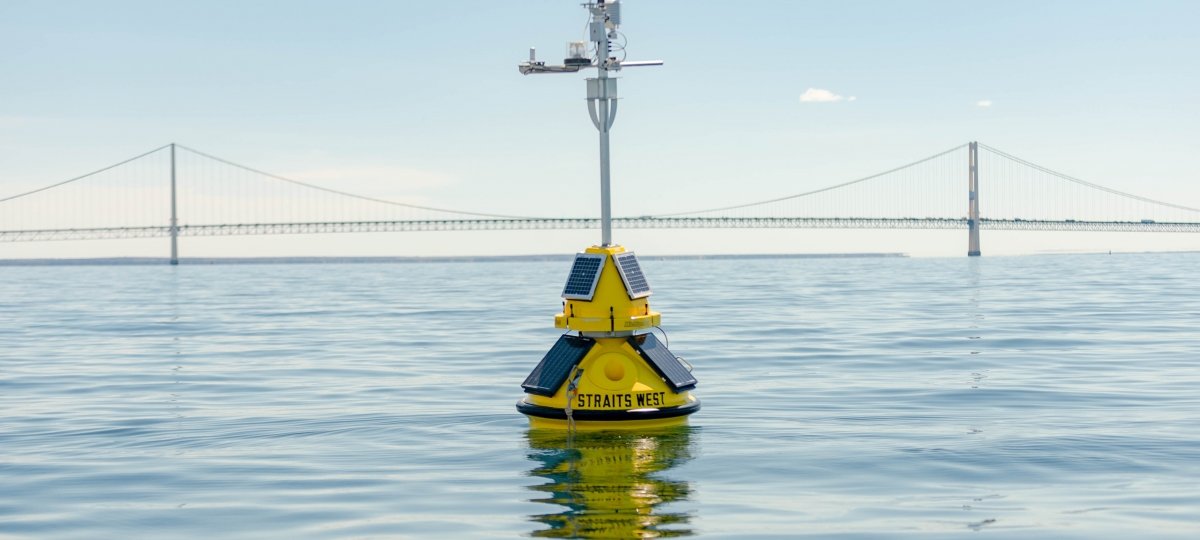 A buoy in the water with the Mackinac Bridge in the background.