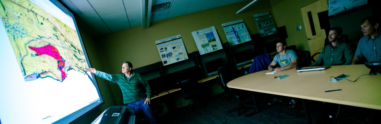 James DeGraff pointing to a displayed map in a conference room.