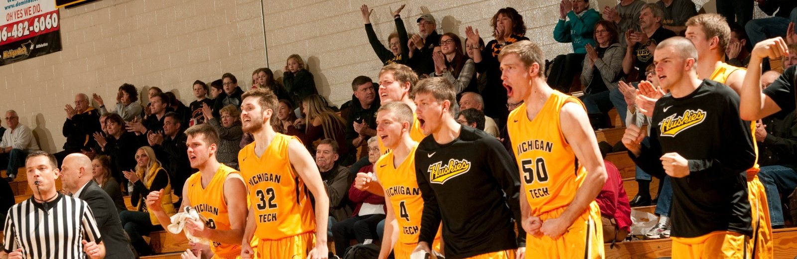 Members of the men's basketball team cheer from the sidelines.