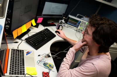A student looks intently at an array of computer monitors displaying coursework.