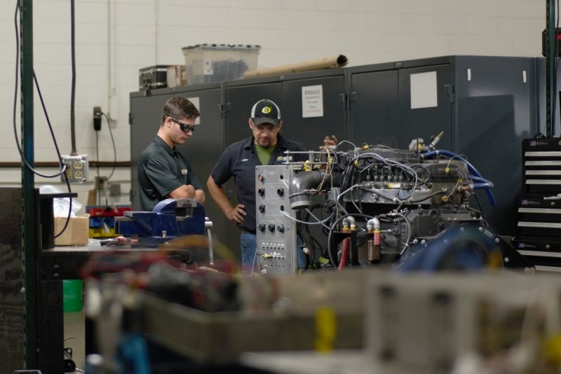 Two engineers look at a giant electrified engine.