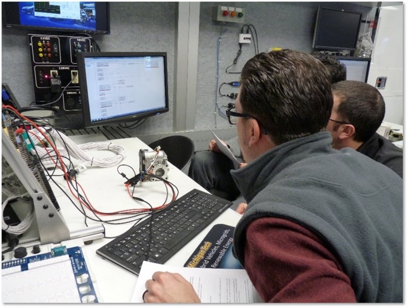 Two engineers working at a computer station inside the APS Mobile Lab