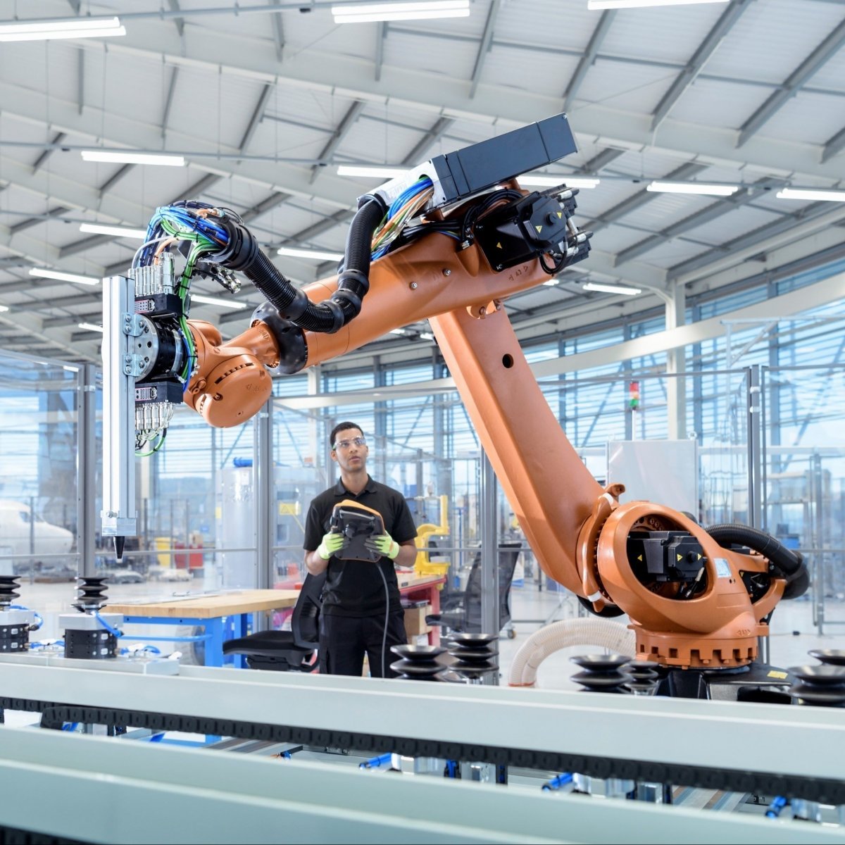 Engineer working in a factory with a robotic arm.
