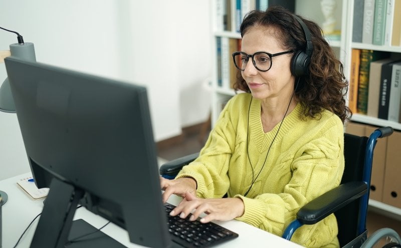 An older student in a wheelchair who is working on their online course.