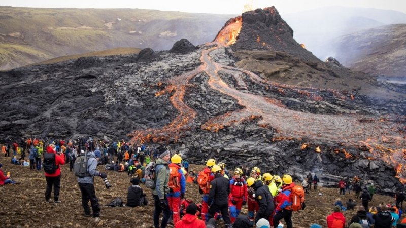 Engineers and experts standing at the base of a volcanic eruption.